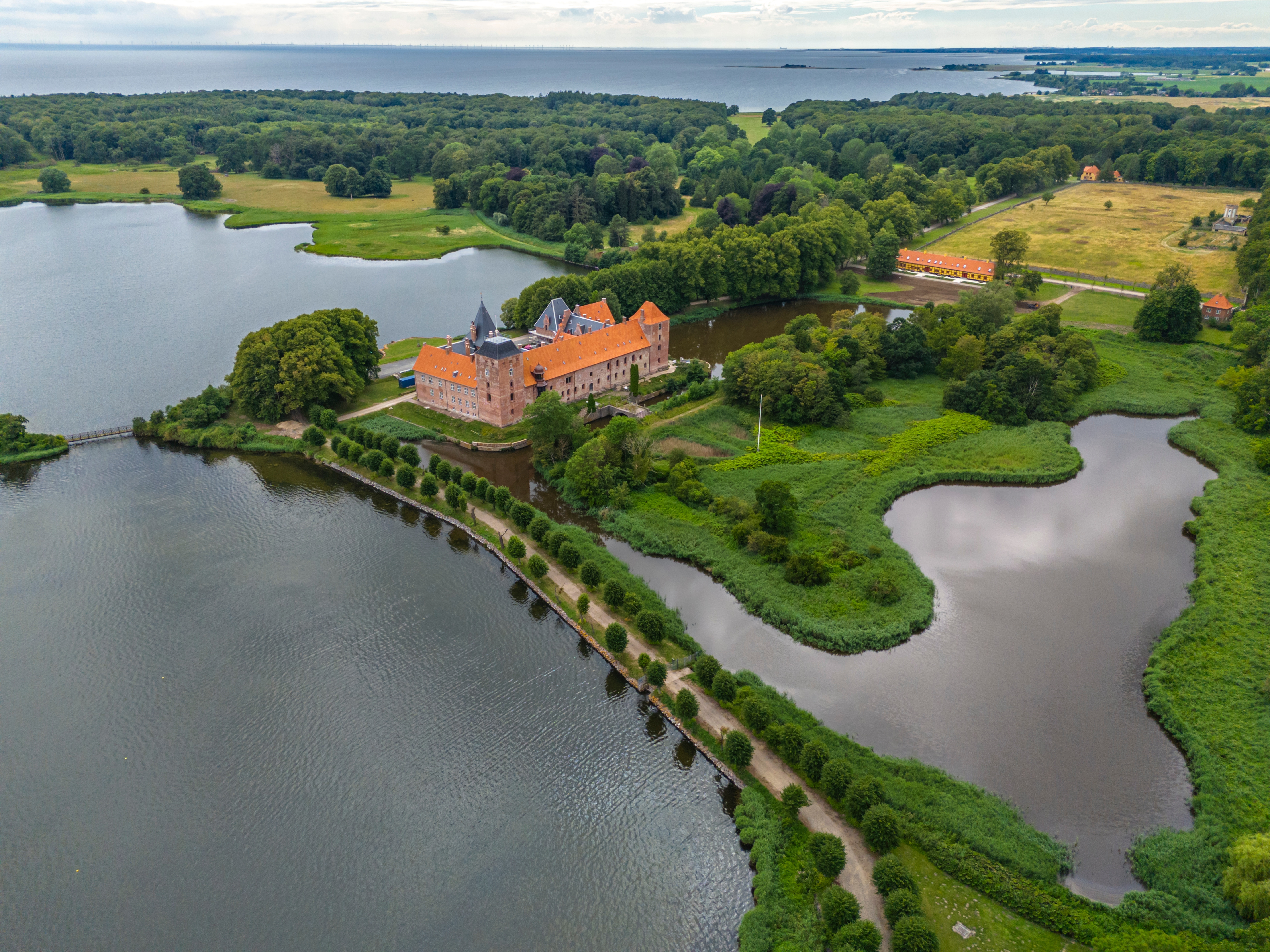 Luftfoto af Aalholm Slot omgivet af søer og grønne skove i Nysted på Lolland, Danmark