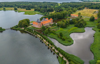 Luftfoto af Aalholm Slot omgivet af søer og grønne skove i Nysted på Lolland, Danmark