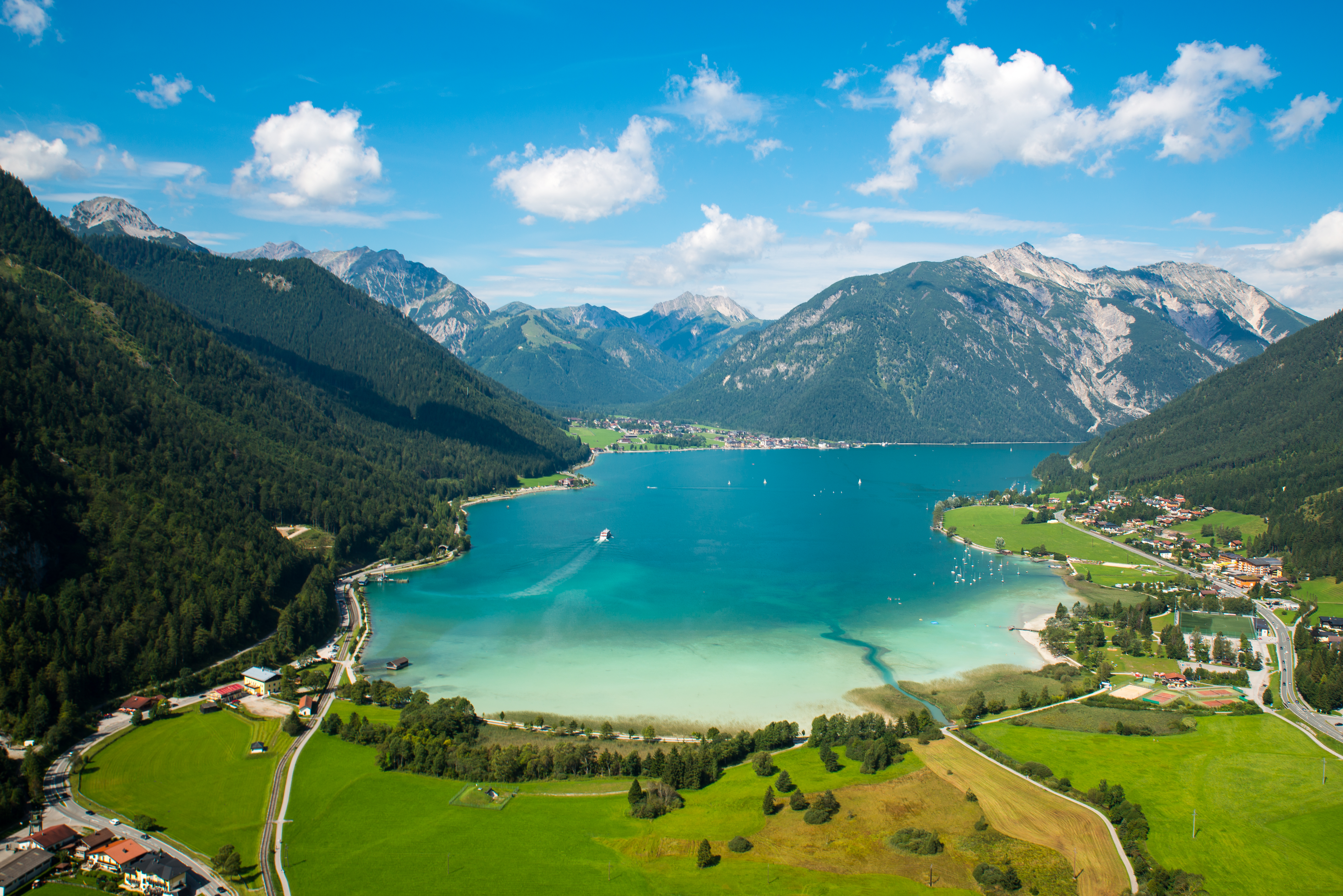 Spektakulær luftfoto af Achensee sø i de østrigske alper med turkisblåt vand og grønne enge