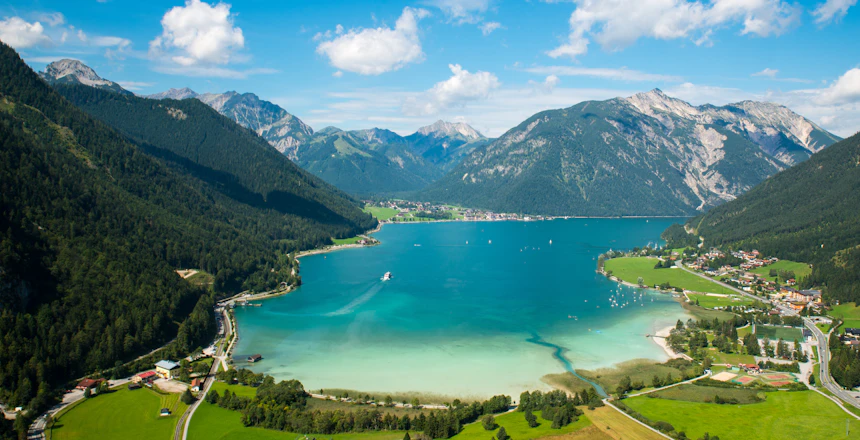 Spektakulær luftfoto af Achensee sø i de østrigske alper med turkisblåt vand og grønne enge