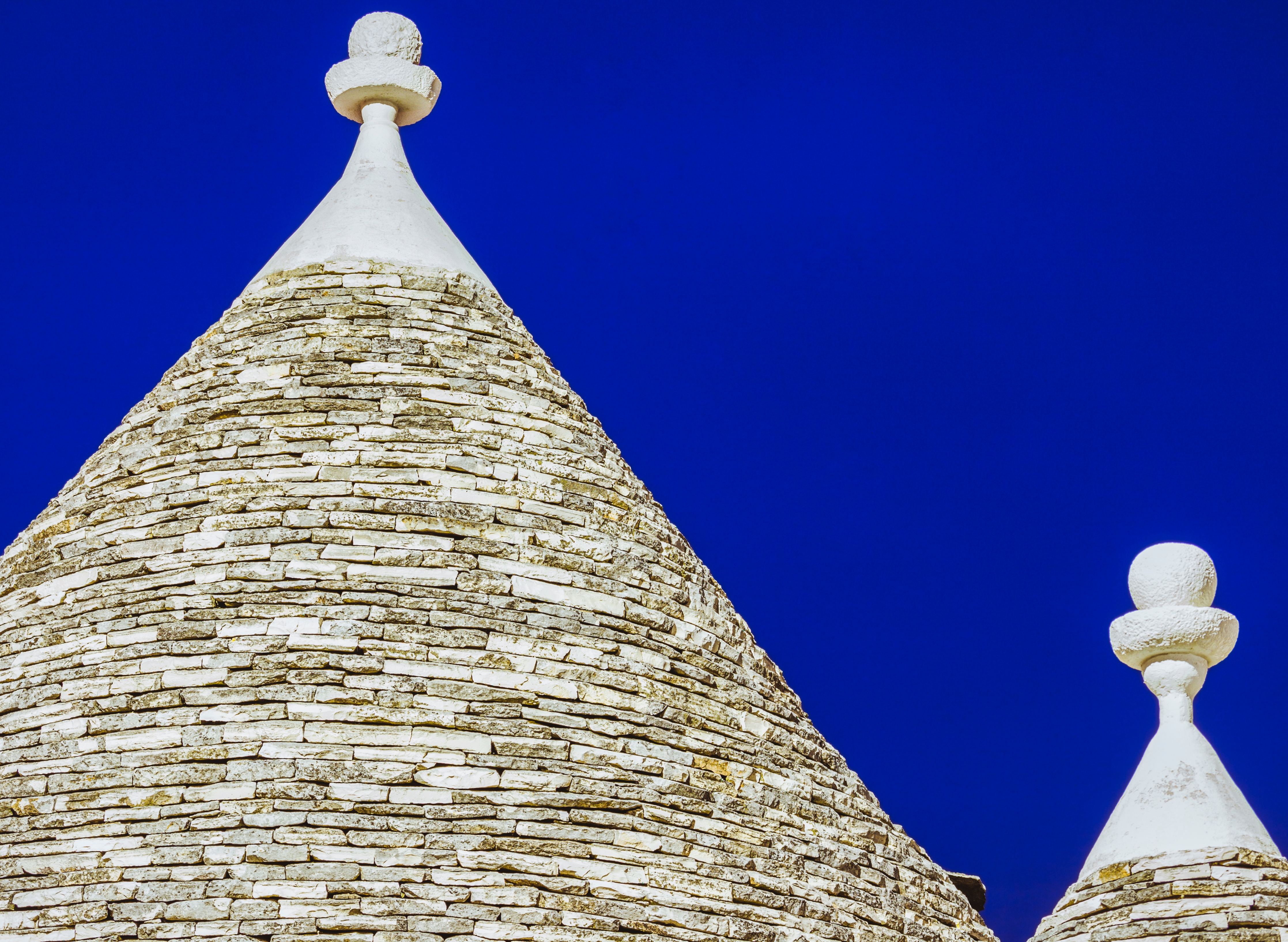 Traditionelle trulli huse med koniske stentage mod dyb blå himmel i Alberobello, Puglia, Italien