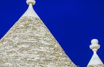 Traditionelle trulli huse med koniske stentage mod dyb blå himmel i Alberobello, Puglia, Italien