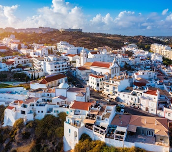 Luftfoto af Albufeira med dens brede sandstrand, hvide bygninger og imponerende kystlinje langs Atlanterhavet i Algarve, Portugal