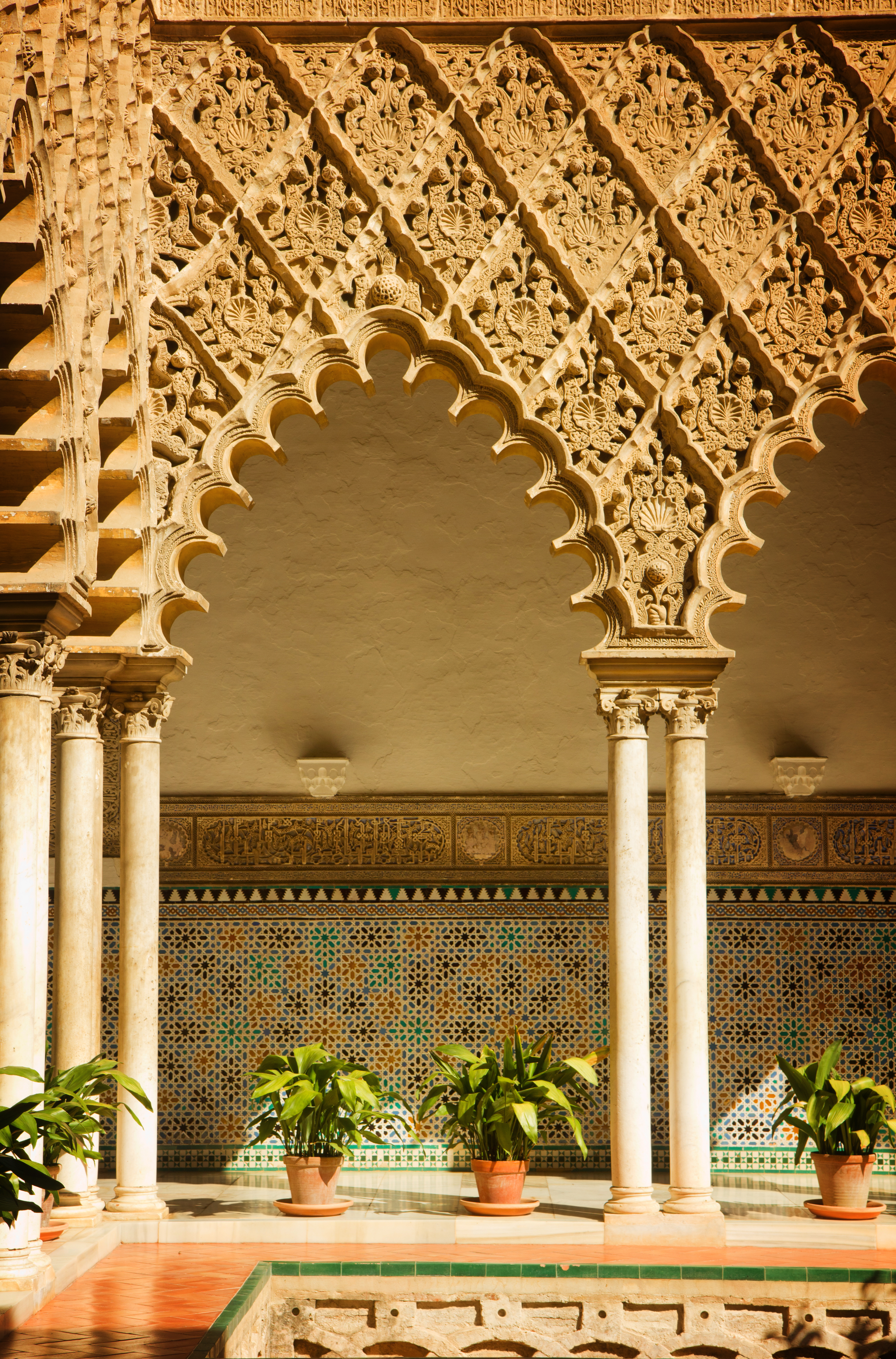 Smukke mauriske buer og udskåret stendekoration i Alcazar paladsets gård i Sevilla, Spanien