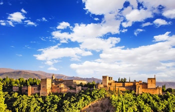 Den historiske Alhambra-fæstning i Granada med solnedgang over bjergene i Andalusien, Spanien