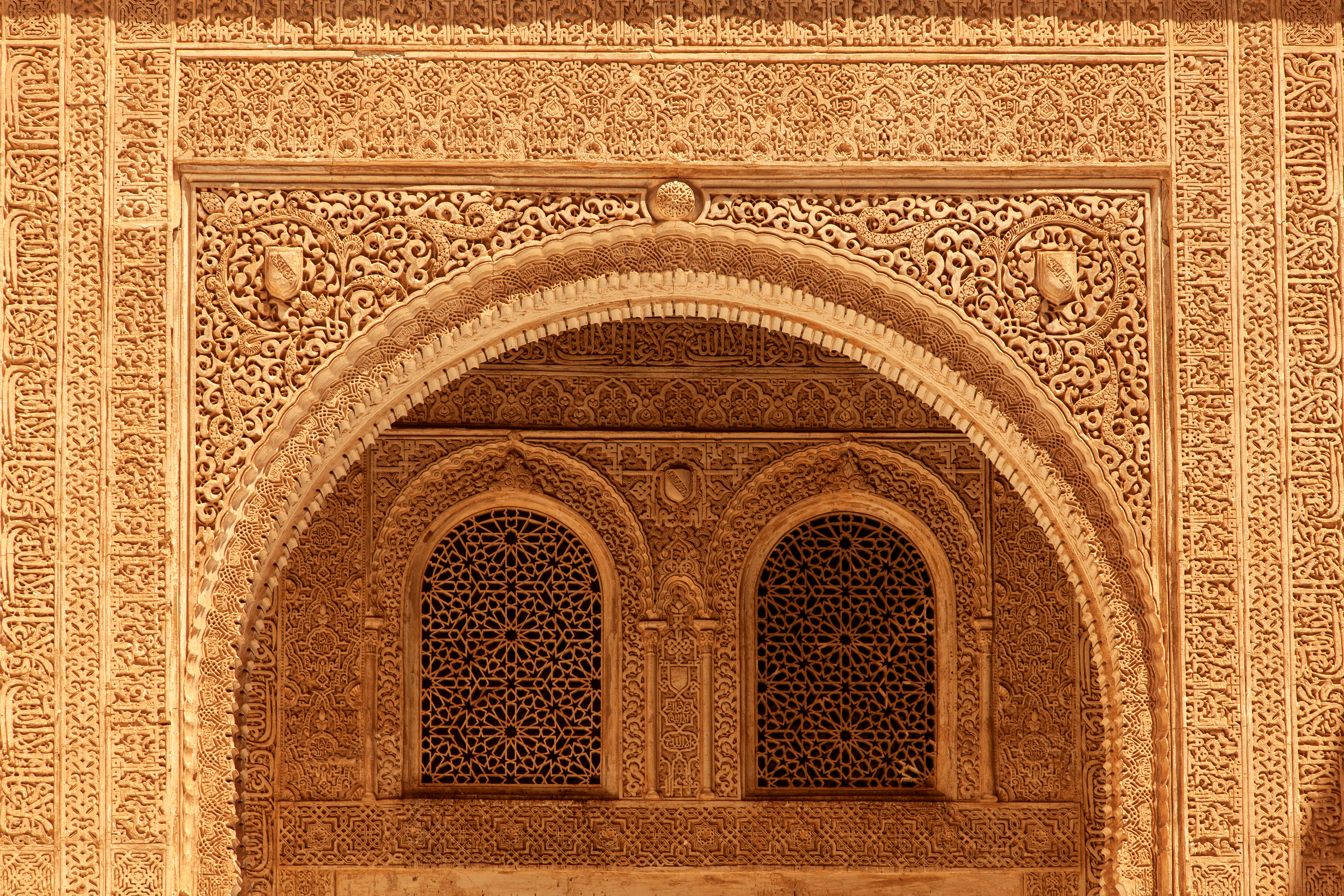 Detaljeret islamisk arkitektur med ornamenterede buer og geometriske mønstre på Alhambra Palads i Granada