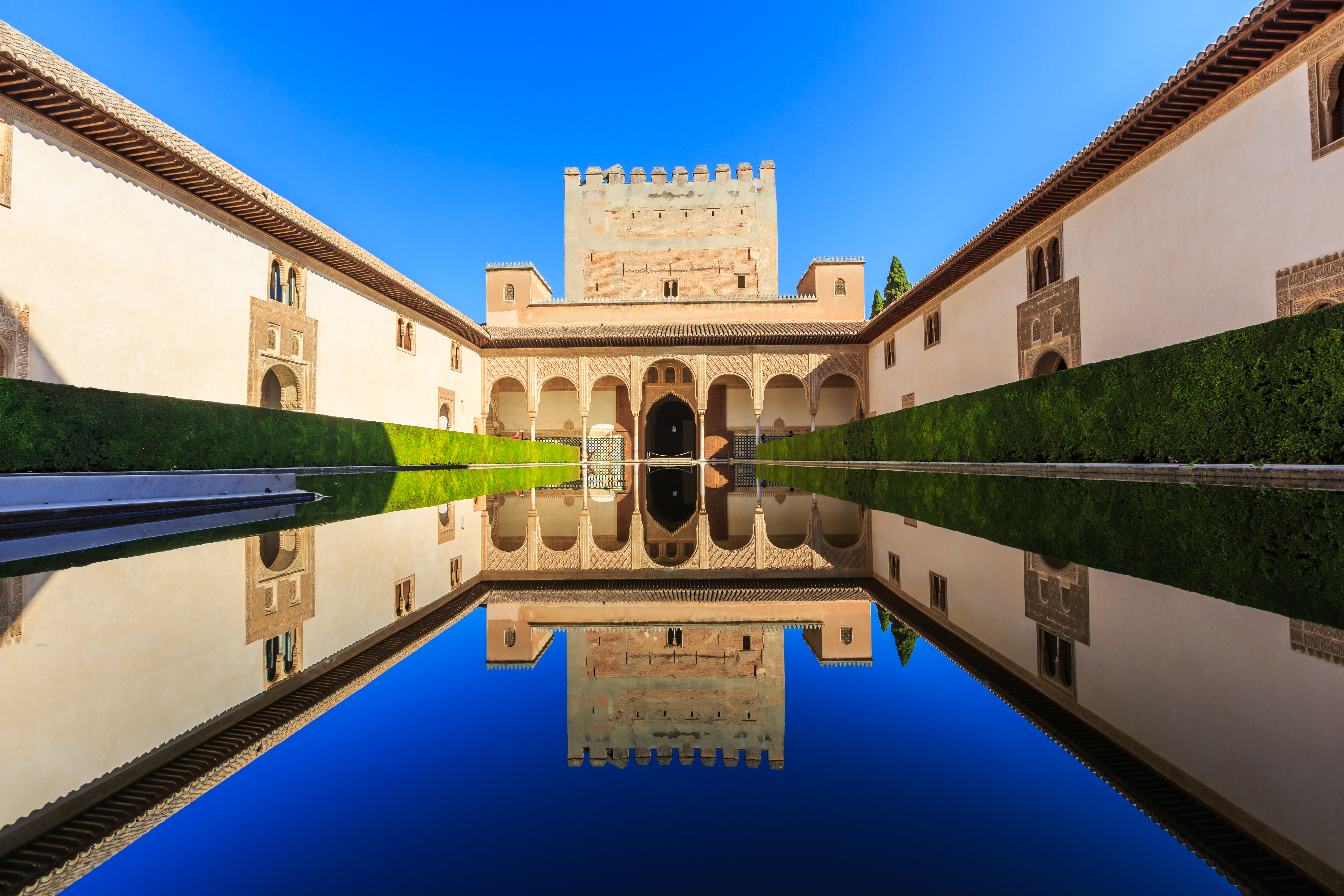 Alhambra-paladset i Granada med det smukke mauriske vandbassiner der reflekterer den historiske arkitektur under en klar blå himmel