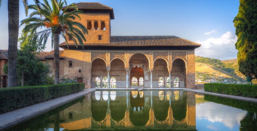 Fredfyldt gårdhave med spejlbassin i Alhambra-paladset, der viser den mauriske arkitektur i Granada, Spanien