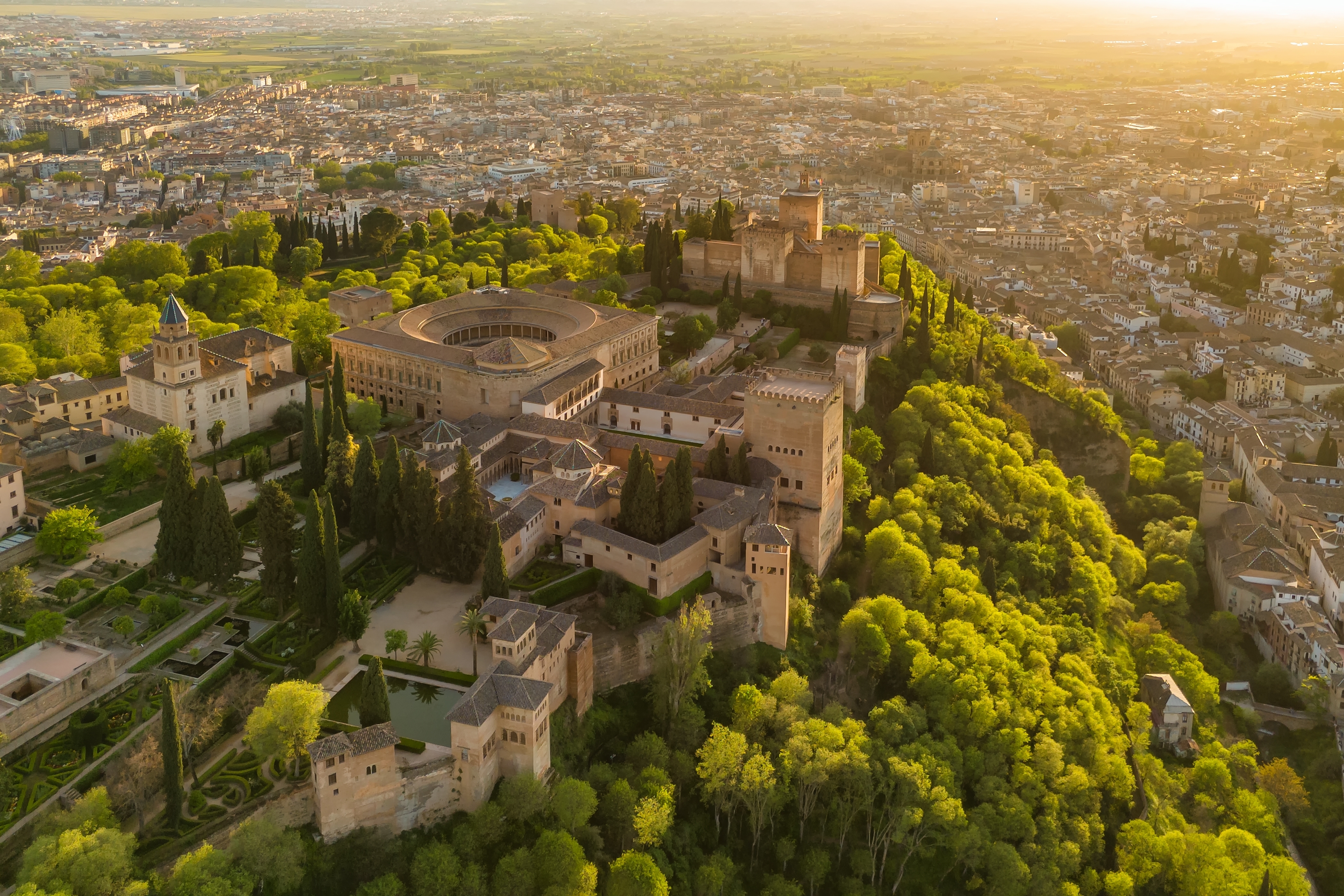 Luftfoto af det historiske Alhambra-palads ved solnedgang i Granada, Andalusien, med udsigt over byens skyline