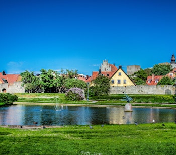 Idyllisk sommerudsigt over Almedalen park i Visby på Gotland med historiske bygninger og grønne områder ved vandet