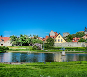 Idyllisk sommerudsigt over Almedalen park i Visby på Gotland med historiske bygninger og grønne områder ved vandet