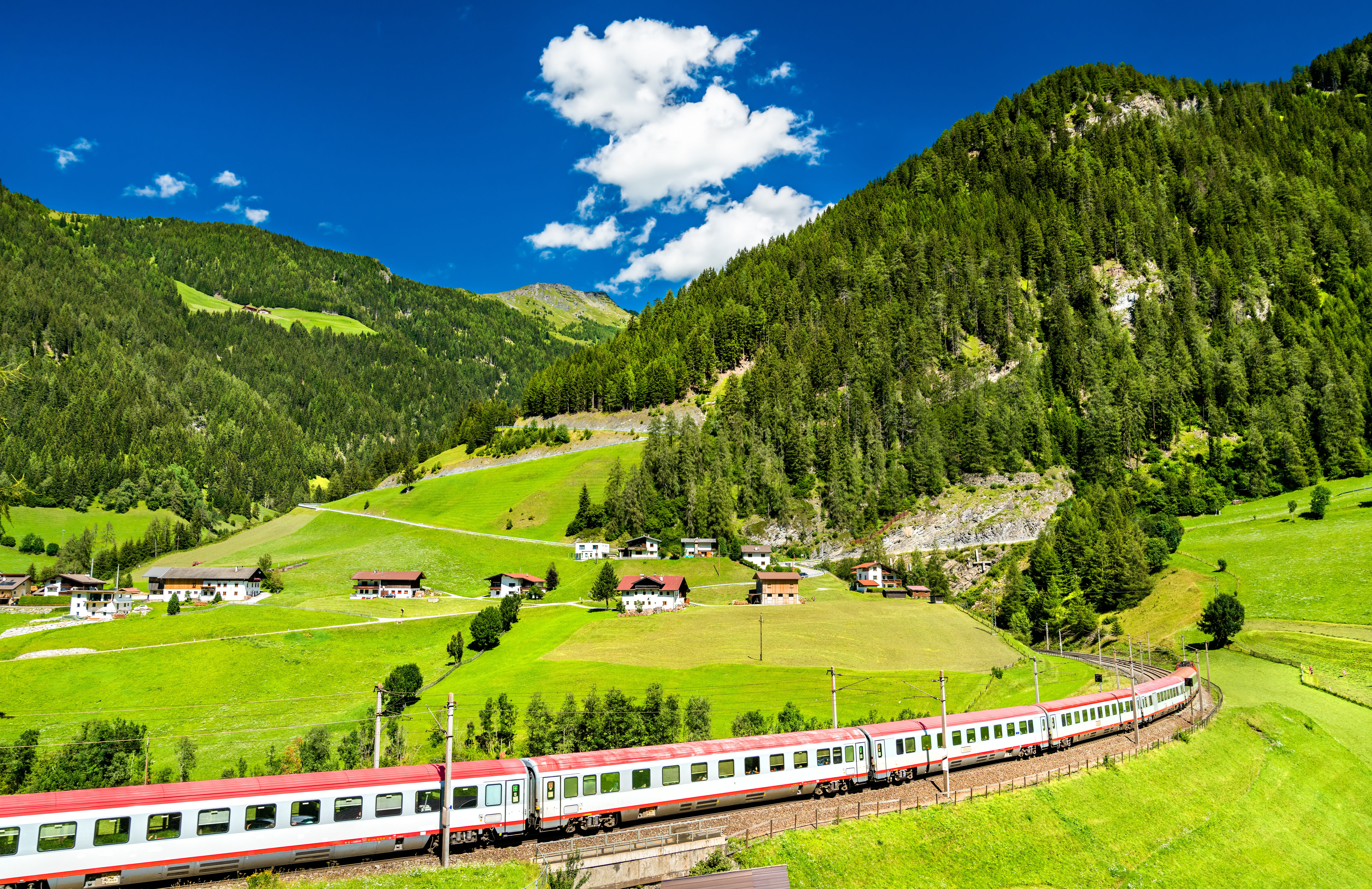 Østrisk alpetog gennem grøn bjergdal i Tyrol med naturskønt landskab