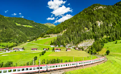 Østrisk alpetog gennem grøn bjergdal i Tyrol med naturskønt landskab