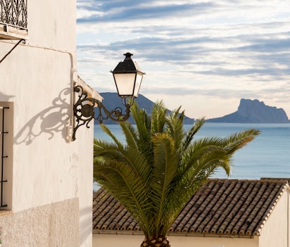 Idyllisk udsigt over Altea-bugten fra den gamle bydel, med traditionelle hvidkalkede huse og terrakotta-teglsten, der skuer ud over det rolige Middelhav med Penon de Ifach-klippen i horisonten