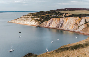 Alum Bay på Isle of Wight med sejlbåde og dramatiske kridtklipper ved den engelske kanal