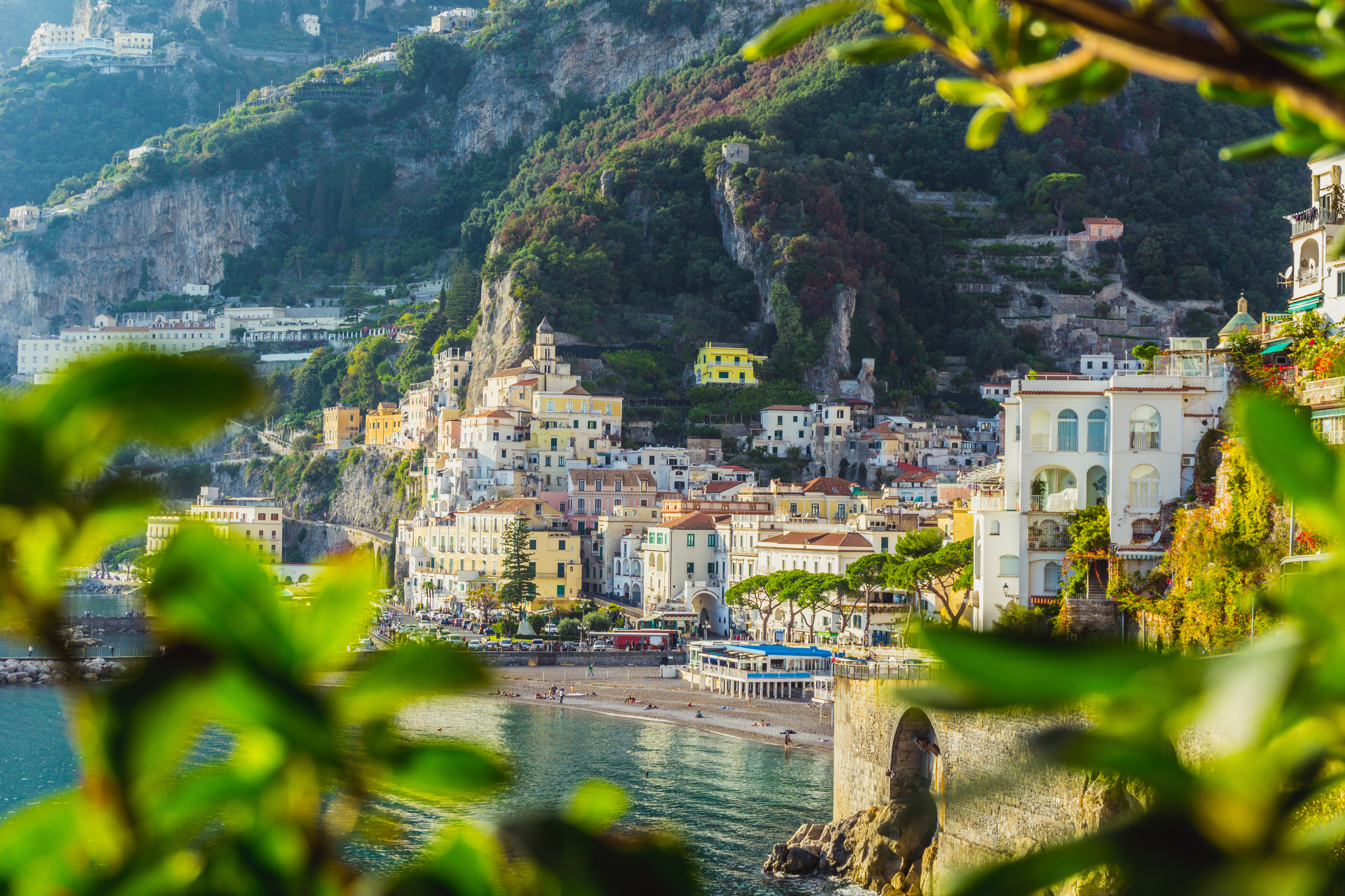 Betagende panoramaudsigt over den historiske by Amalfi i Campania, med farverige bygninger der trapper ned ad bjergsiden mod den blå Middelhavsbugt og de karakteristiske klipper