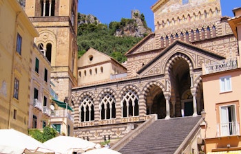 Den historiske Amalfi Katedral med imponerende facade i den solrige kystby i Campania, Italien, omgivet af udendørs caféer