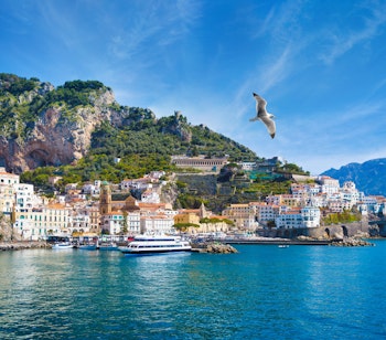 Betagende panoramaudsigt over Amalfi i Italien med farverige bygninger på klippesiden og det azurblå Middelhav under en klar himmel