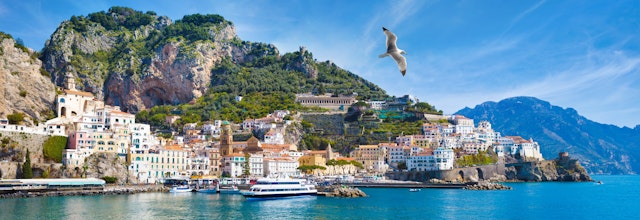 Betagende panoramaudsigt over Amalfi i Italien med farverige bygninger på klippesiden og det azurblå Middelhav under en klar himmel
