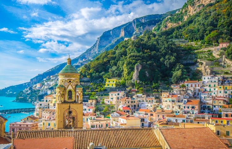 Betagende udsigt over Amalfi-byen med dens farverige huse, der kaskader ned ad de stejle skråninger mod det turkisblå Middelhav langs den berømte Amalfikyst i Italien