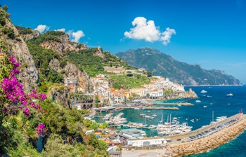 Betagende udsigt over Amalfi by med farverige bygninger mellem stejle klipper og det azurblå Middelhav på den berømte Amalfikyst