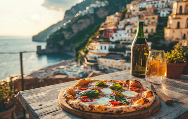 Italiensk pizza med mozzarella og basilikum på træbord med udsigt over Amalfikysten ved solnedgang