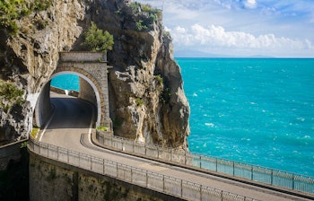 Panoramaudsigt over den berømte Amalfi-kystvej i Italien med dramatiske klipper, snoet vej langs kysten og det azurblå Middelhav - perfekt sommerferiemål