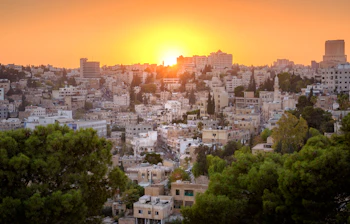 Romerske ruiner i Amman Citadel-parken ved solnedgang med panoramaudsigt over Jordans hovedstad og den historiske gamle bydel
