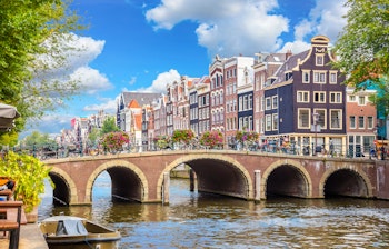 Idyllisk udsigt over Amsterdams centrum med traditionelle hollandske huse langs Amstel-floden og en historisk bro, der krydser vandet