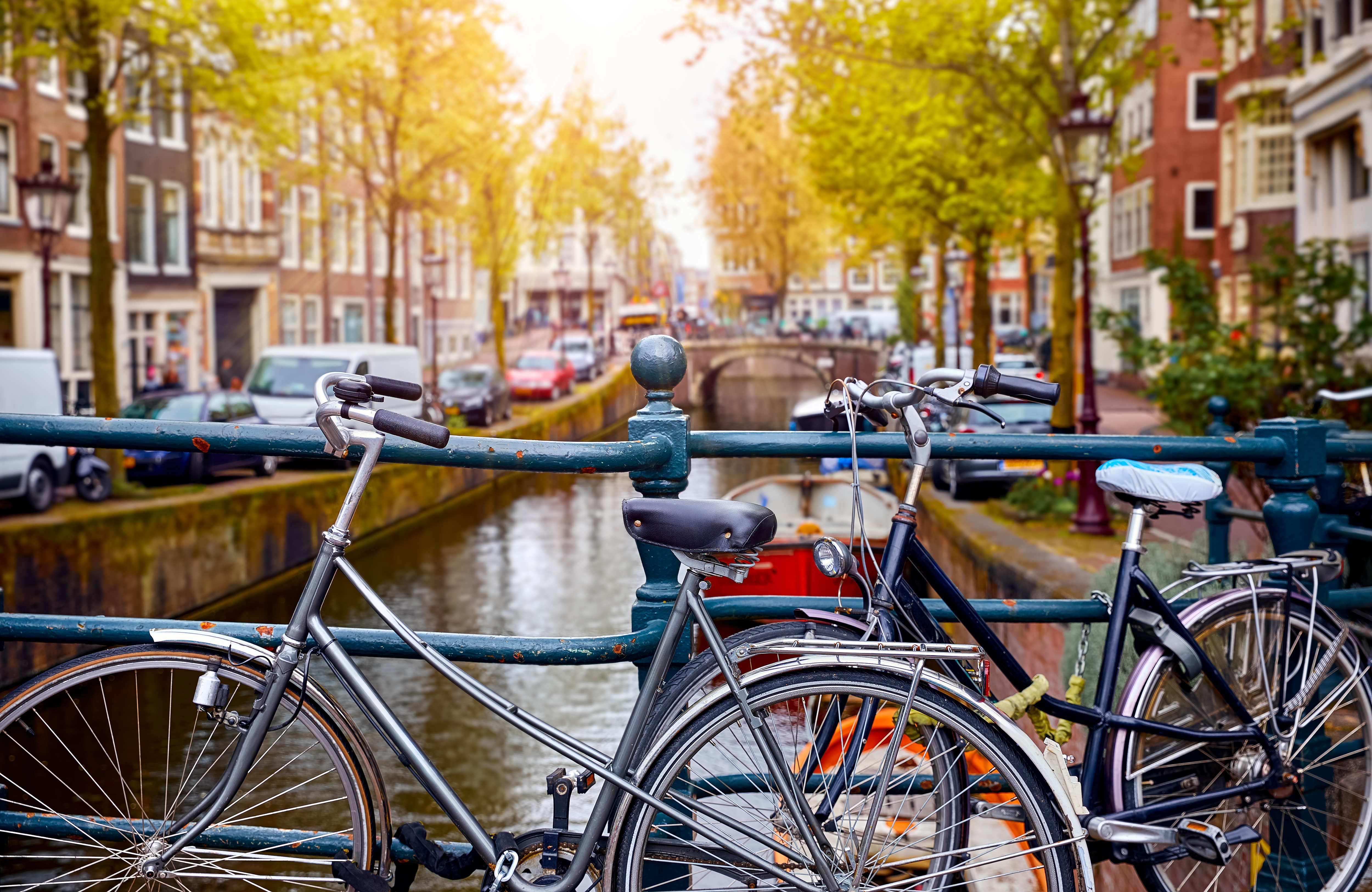 Traditionelle hollandske cykler parkeret langs Amsterdam kanal med historiske huse og efteraarstrae