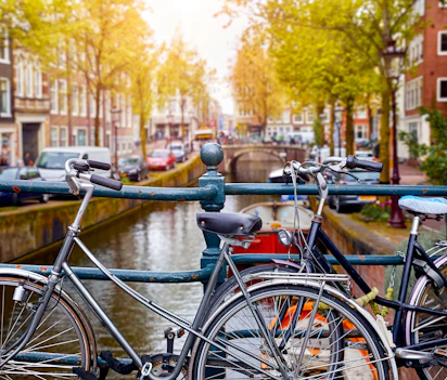 Traditionelle hollandske cykler parkeret langs Amsterdam kanal med historiske huse og efteraarstrae