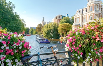Idyllisk kanalscene i Amsterdam med farverige historiske bygninger, der spejler sig i vandet - en klassisk oplevelse i Hollands hovedstad