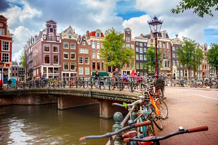 Idyllisk kanalscene i Amsterdam med traditionelle hollandske huse, cykler og både langs vandet i byens historiske centrum