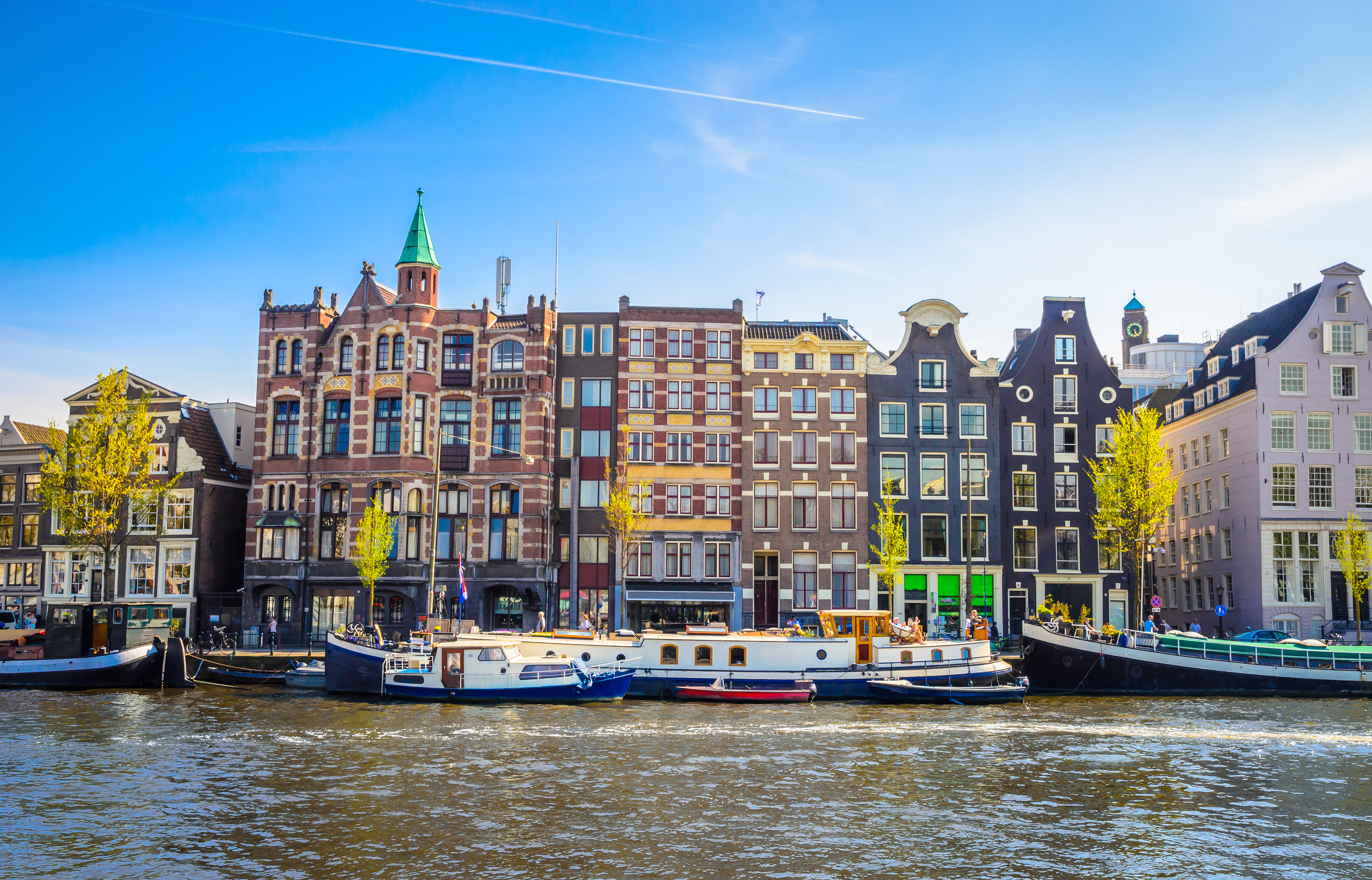 Traditionelle hollandske kanalhuse og både langs Amsterdams vandfront i Nederlandene