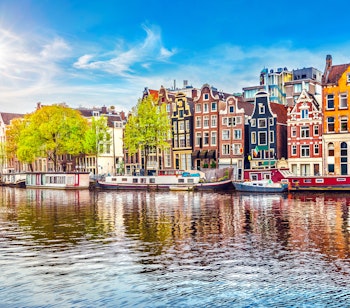 Farverige kanalhuse og både langs Amsterdam kanal på solskinsdag