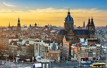 Stemningsfuld vintersolnedgang over Amsterdams historiske skyline med traditionel hollandsk arkitektur silhuet mod den gyldne aftenhimmel