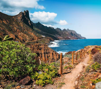 Malerisk vandrevej gennem det klippefyldte landskab i Anaga Nationalpark med bjergkæder og Atlanterhavets blå bølger på Tenerife, UNESCO verdensarv