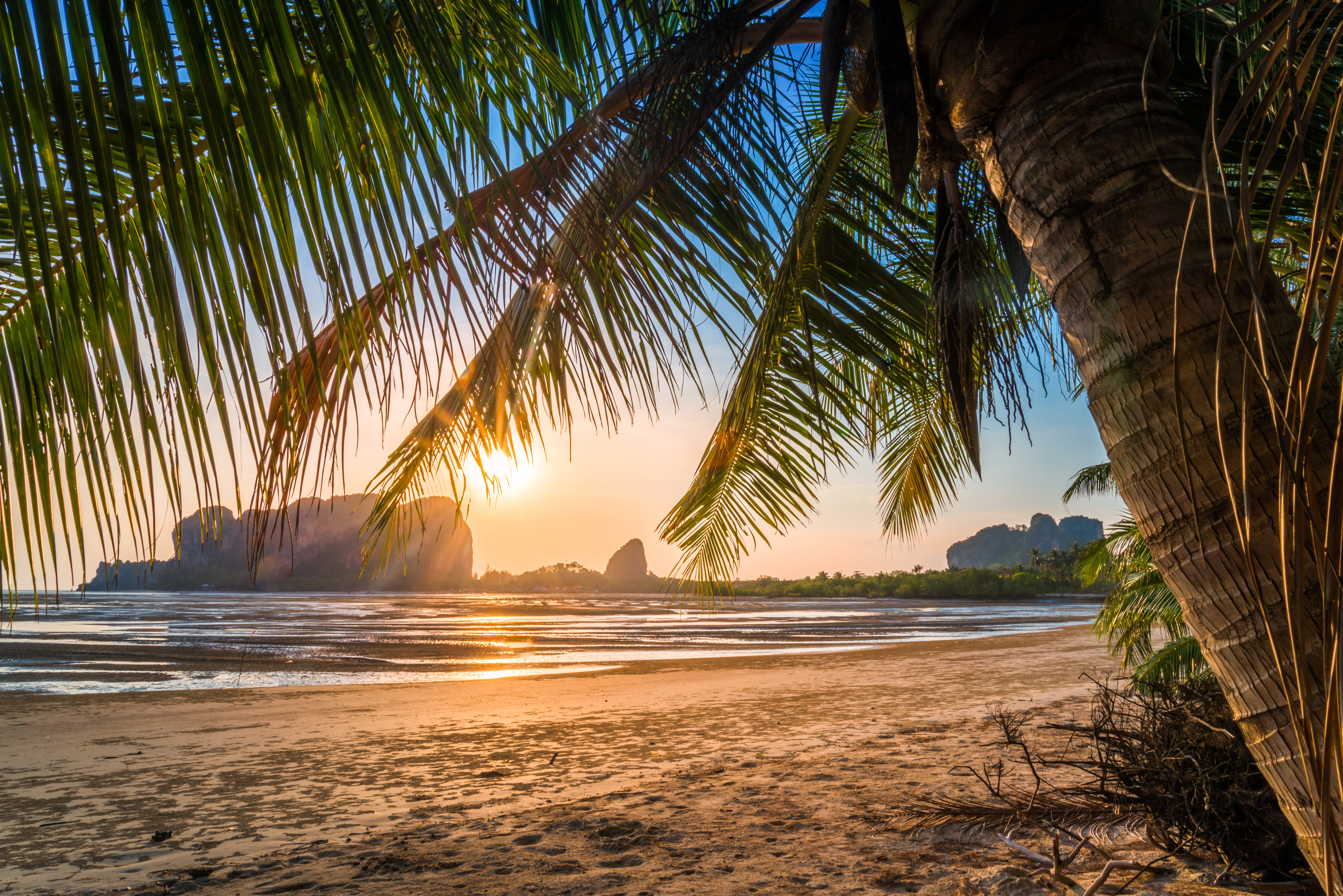 Betagende solnedgang over Andamanhavet i Trang-provinsen, Thailand, hvor den gyldne sol kaster et magisk lys over det turkisblå vand og den tropiske strand, perfekt for en afslappende ferie i Sydøstasien