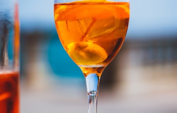 Forfriskende Aperol Spritz cocktail serveret udendørs i Taormina med smuk blå himmel i baggrunden