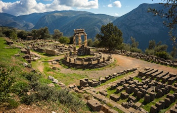 Historiske ruiner af Apollons tempel i Delphi, Grækenland med ikoniske stensøjler omgivet af bjerglandskab - en vigtig seværdighed fra antikkens Grækenland