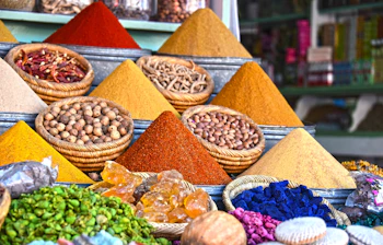 Farverige krydderier i kegleformede bunker på en traditionel arabisk markedsbod i Marrakech - eksotisk udvalg af gurkemeje, spidskommen, paprika og andre krydderier i en marokkansk souk