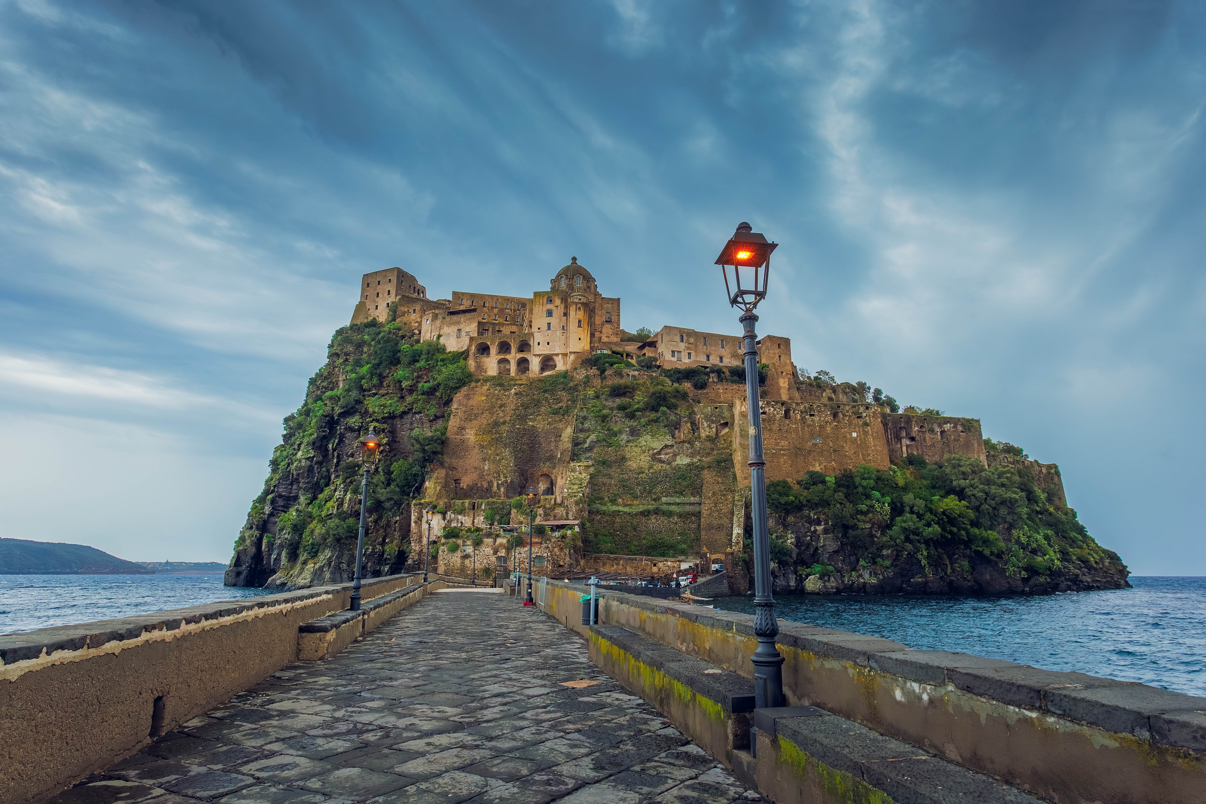 Det historiske Aragonese slot på klippeø ved Ischia i Italien i aftenlys med stenbro i forgrunden