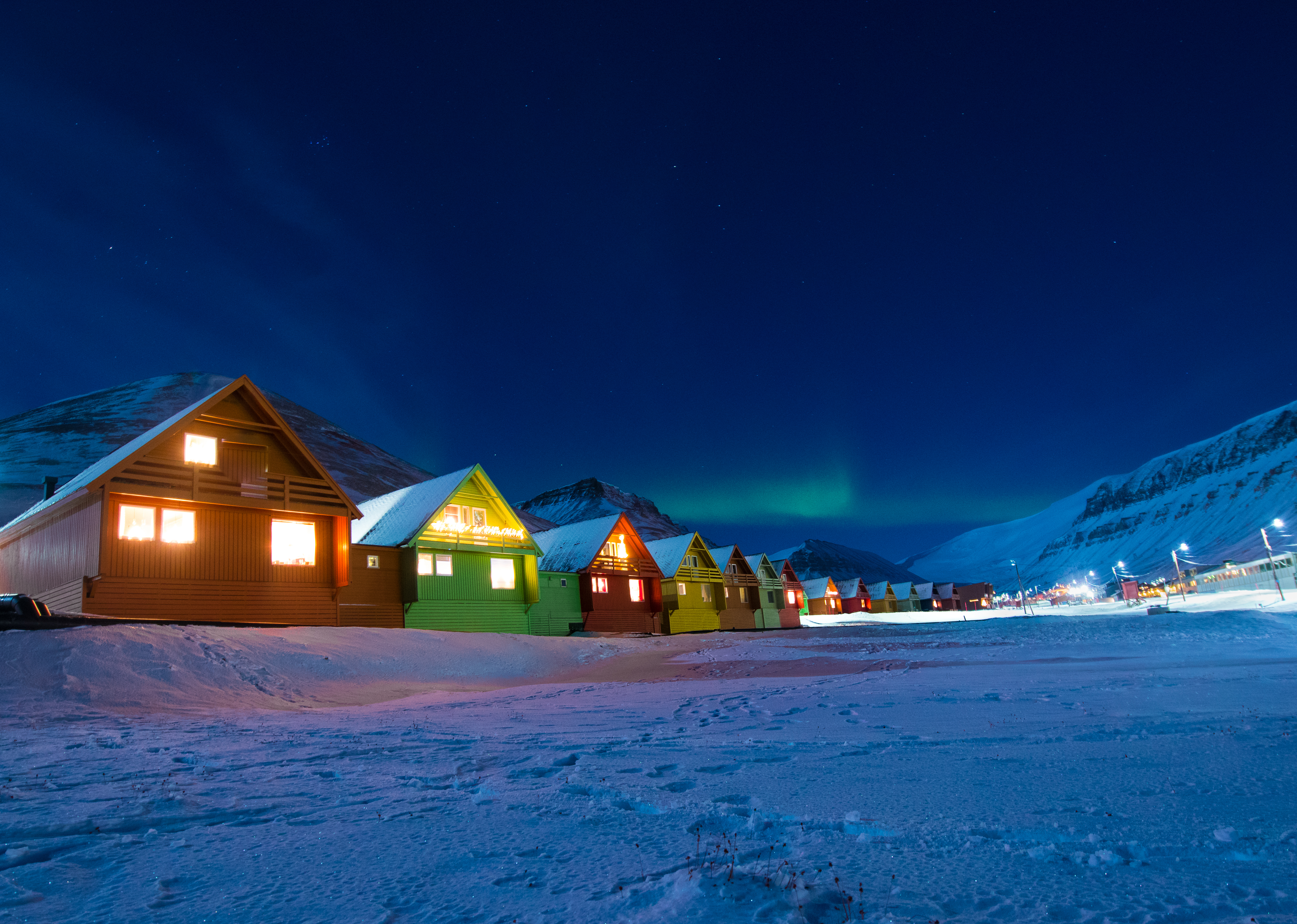 Farverige arktiske huse under nordlys i Svalbard vinter landskab