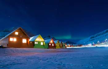 Farverige arktiske huse under nordlys i Svalbard vinter landskab