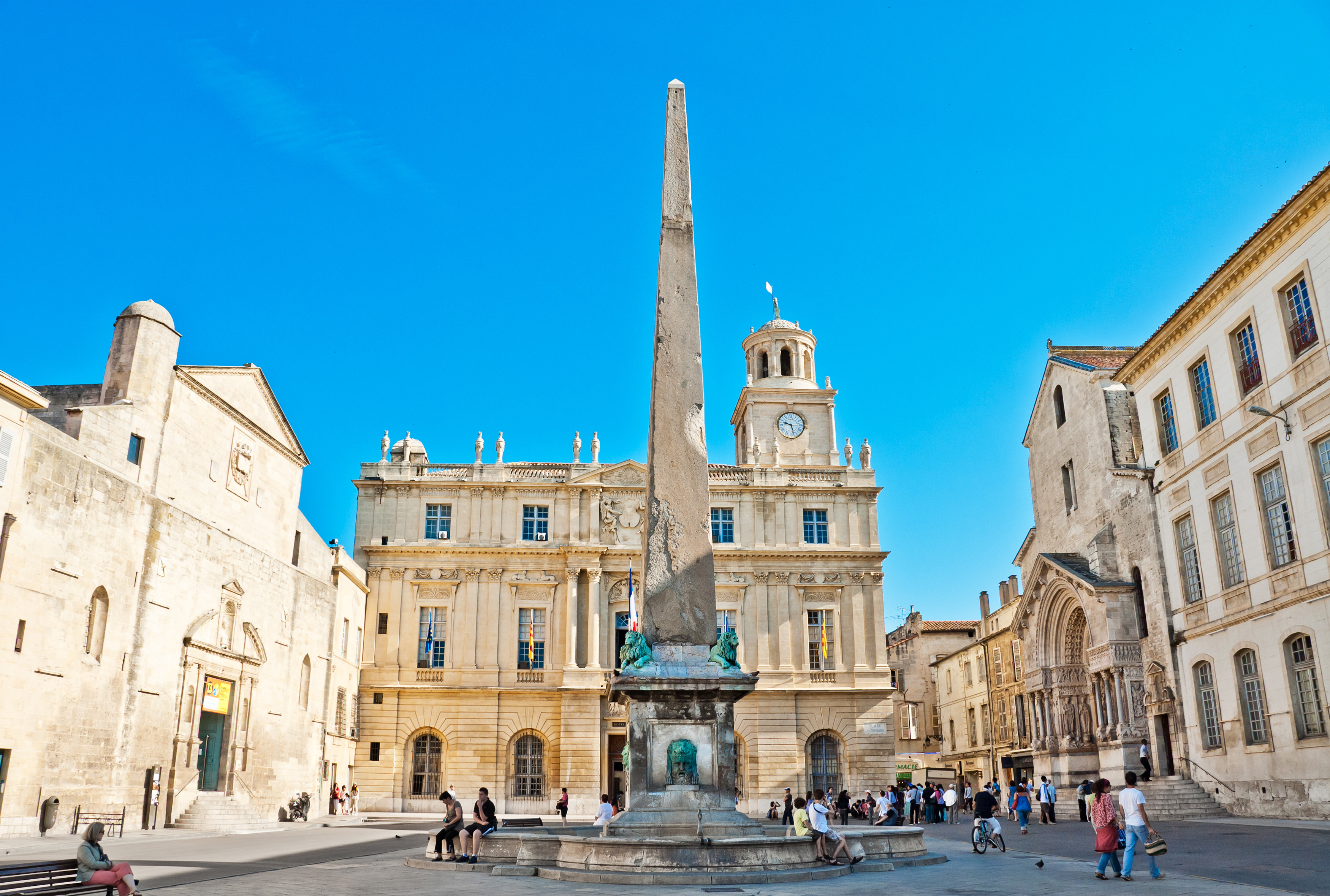 Den historiske Place de la République i Arles, Frankrig, med den antikke obelisk og det klassiske rådhus under en klar blå himmel