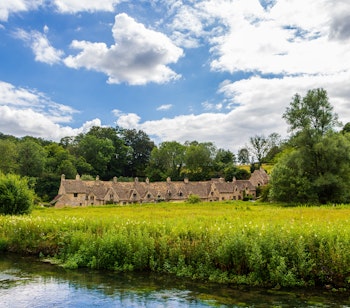 Historiske stenhuse ved Arlington Row langs floden Coln i den idylliske landsby Bibury i Cotswolds, England