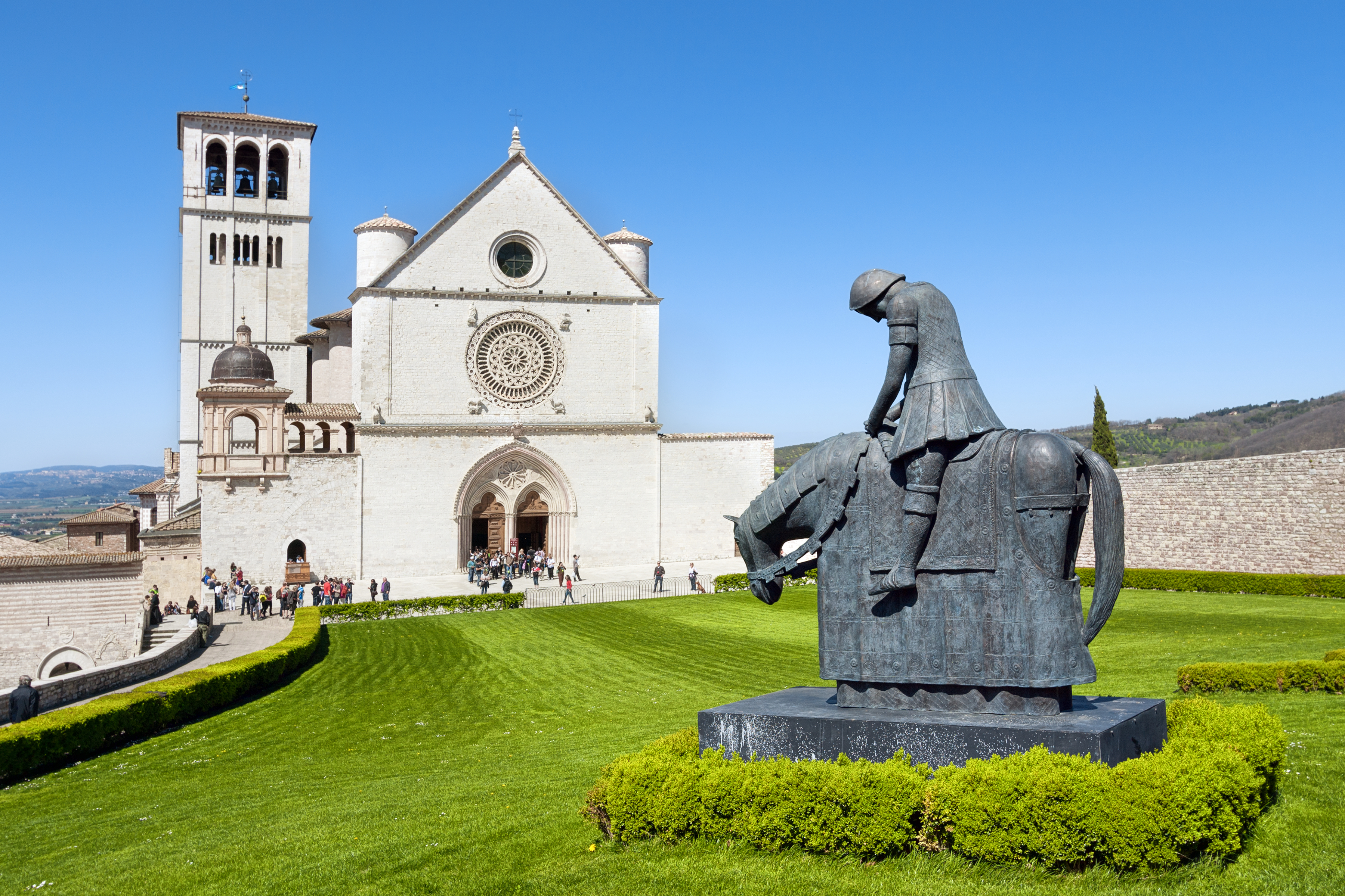 Basilika Sankt Franciscus i Assisi med bronzestatue og middelalderlig arkitektur i Italien