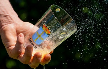 Hånd holder glas med frisk asturisk cider og vandstænk under Spaniens-ferie