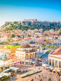 Panoramaudsigt over Athen med Akropolis, Parthenon-templet og Monastiraki-torvet i solnedgangslys, hvor antik græsk historie møder moderne byliv