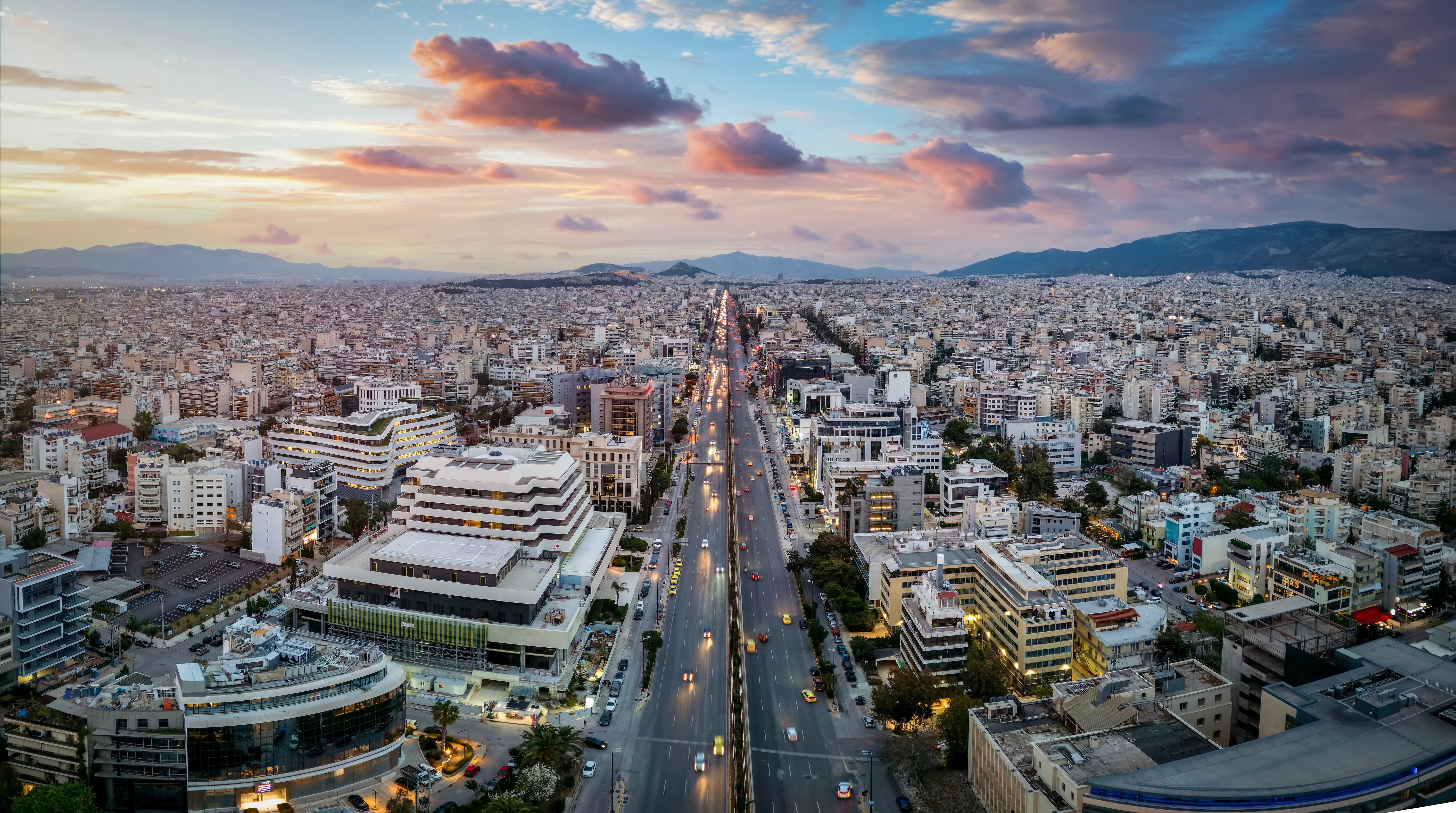Luftfoto af Athens skyline ved solnedgang med Syggrou Avenue der forbinder de sydlige forstæder med Grækenlands historiske hovedstad